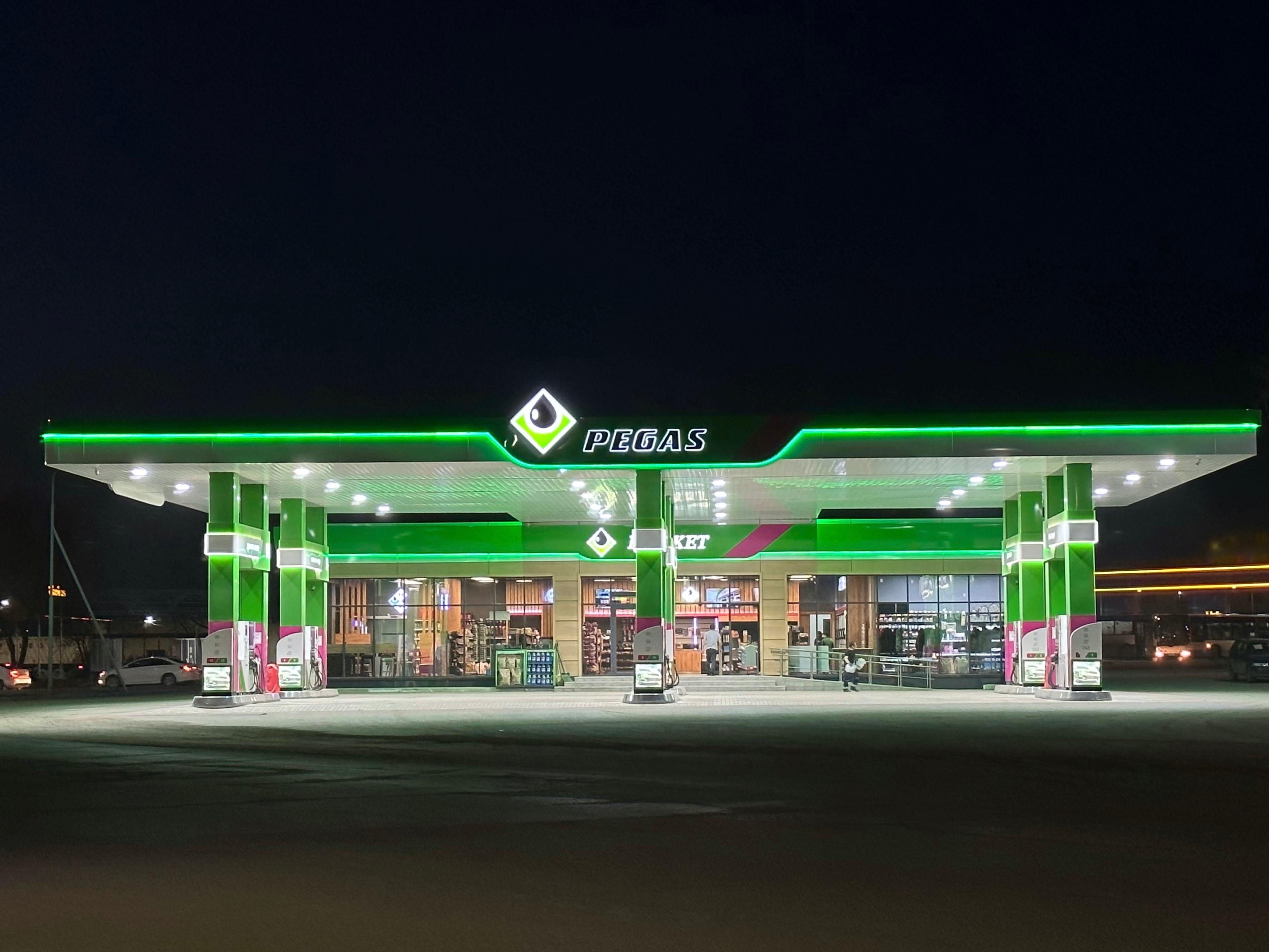 Современная АЗС PEGAS ночью с ярким зеленым освещением